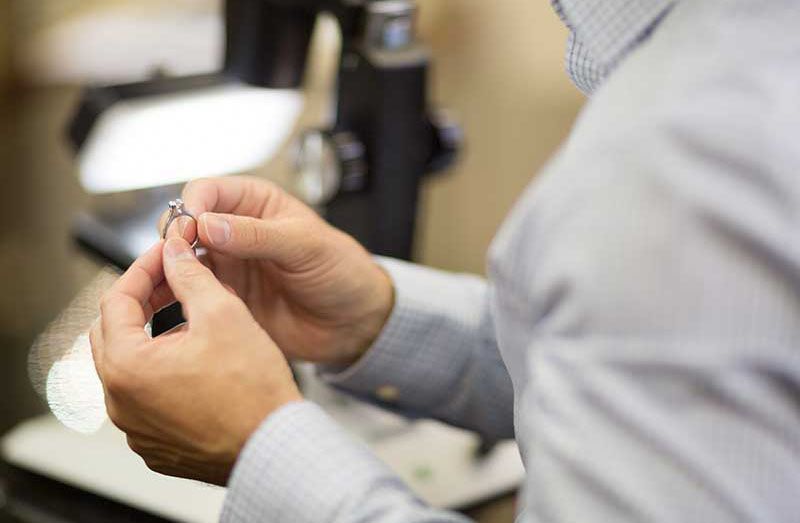 Ron Conrad evaluating a piece of jewelry at Conrad Jewelry